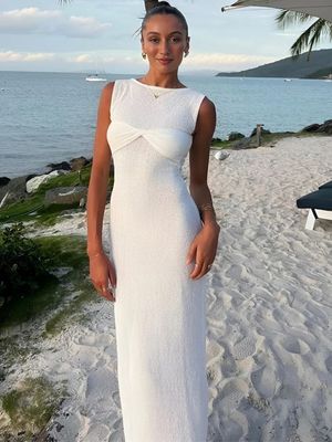 a woman standing on a beach wearing a white dress