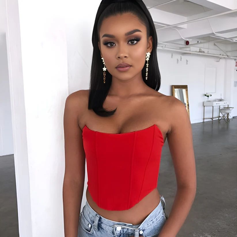a woman in a red top leaning against a wall