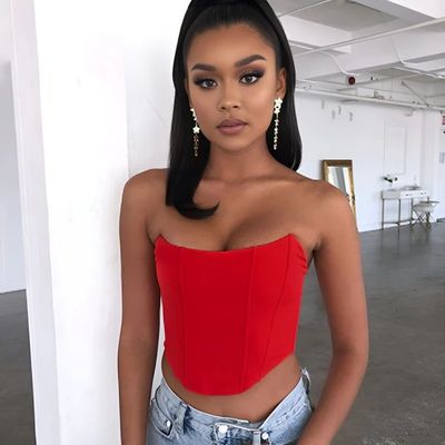 a woman in a red top leaning against a wall