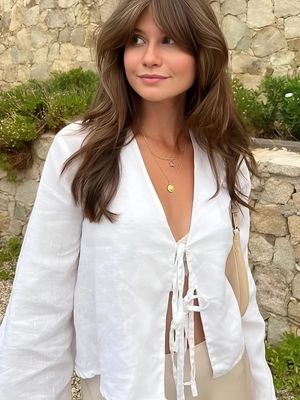 a woman standing in front of a stone wall