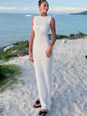 a woman in a white dress standing on a beach