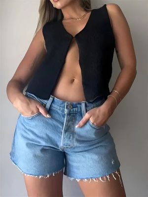 a woman wearing a black top and denim shorts