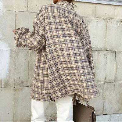 a woman is standing against a wall with a handbag