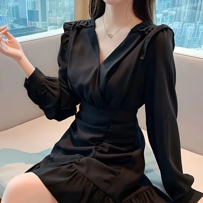 a woman in a black dress sitting on a couch
