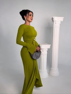 a woman in a green dress standing next to a column