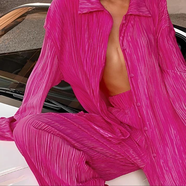 a woman in a pink outfit leaning on a car