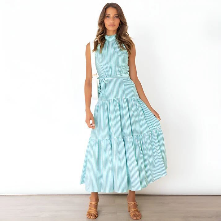 a woman in a blue dress standing in front of a white wall
