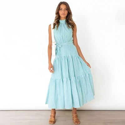 a woman in a blue dress standing in front of a white wall