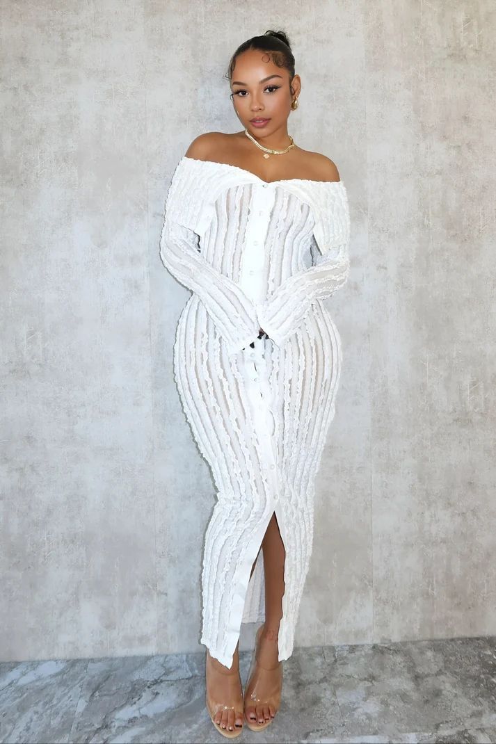 a woman in a white dress standing in front of a wall