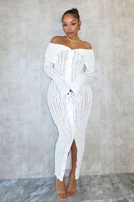 a woman in a white dress standing in front of a wall