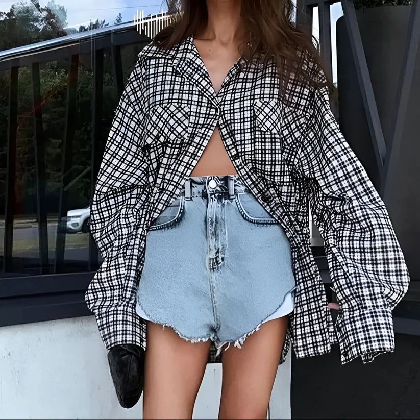 a woman wearing a plaid jacket and denim shorts