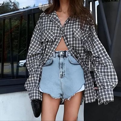 a woman wearing a plaid jacket and denim shorts