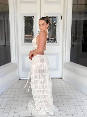 a woman standing in front of a door wearing a white dress