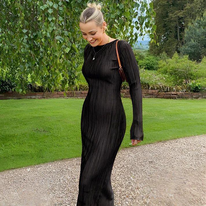 a woman in a black dress walking down a path