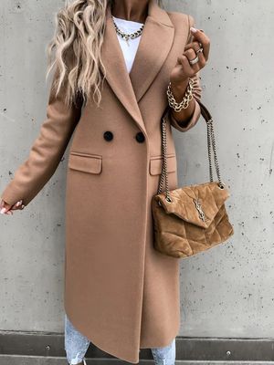 a woman wearing a tan coat and jeans