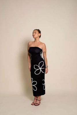 a woman wearing a black dress with white flowers on it