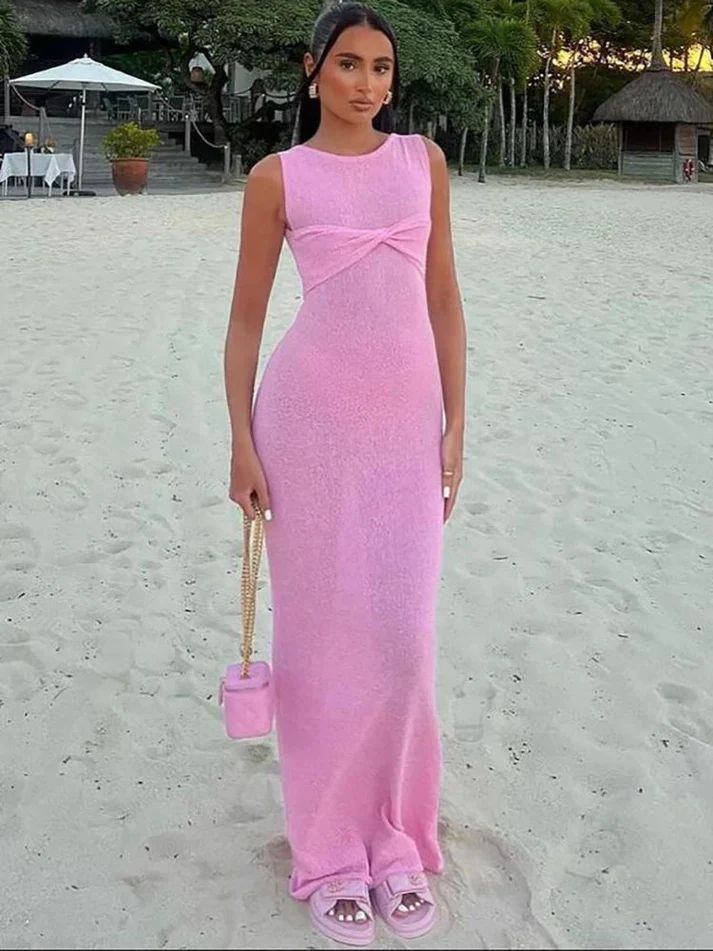 a woman in a pink dress standing on a beach