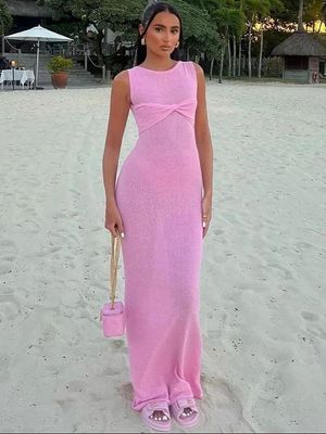 a woman in a pink dress standing on a beach