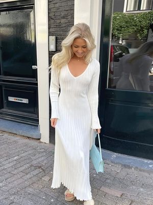 a woman in a white dress is walking down the street