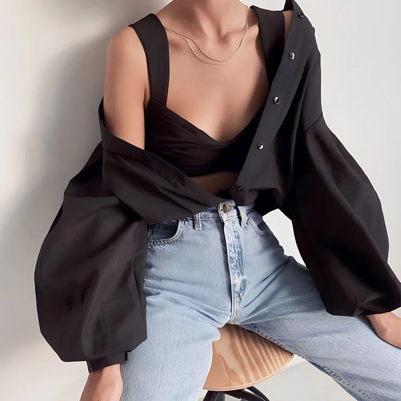 a woman sitting on a stool wearing a black top
