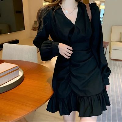 a woman in a black dress standing in front of a table
