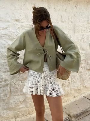 a woman wearing a green blouse and white shorts