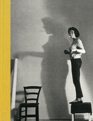 a black and white photo of a woman standing on a chair