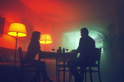 a man and woman sitting at a table in a dark room