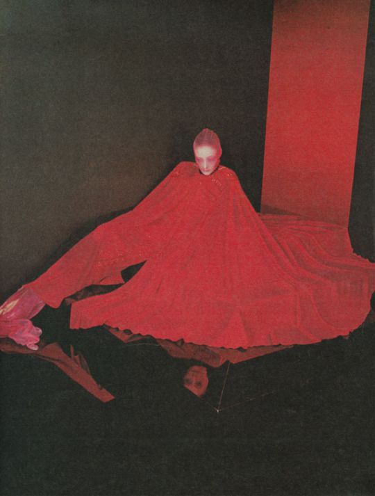 a woman in a red dress sitting on a black floor