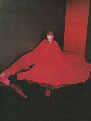 a woman in a red dress sitting on a black floor