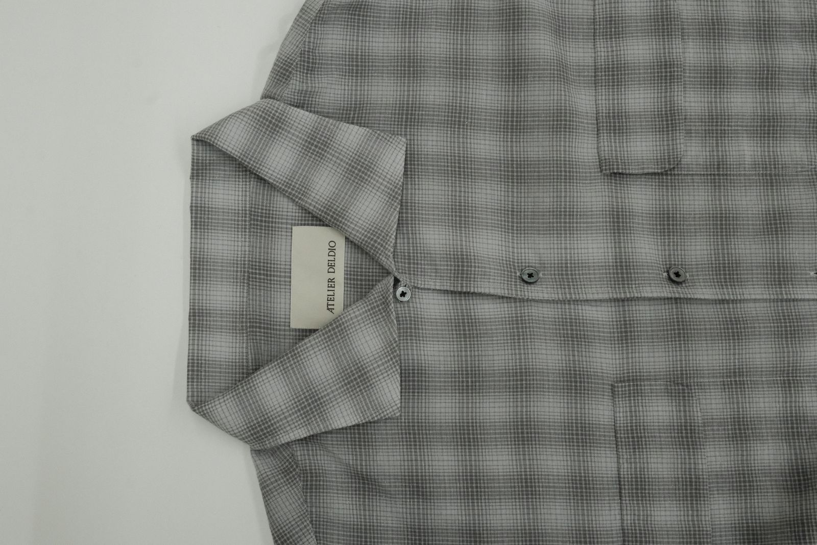 a gray and black checkered shirt with a tag on it