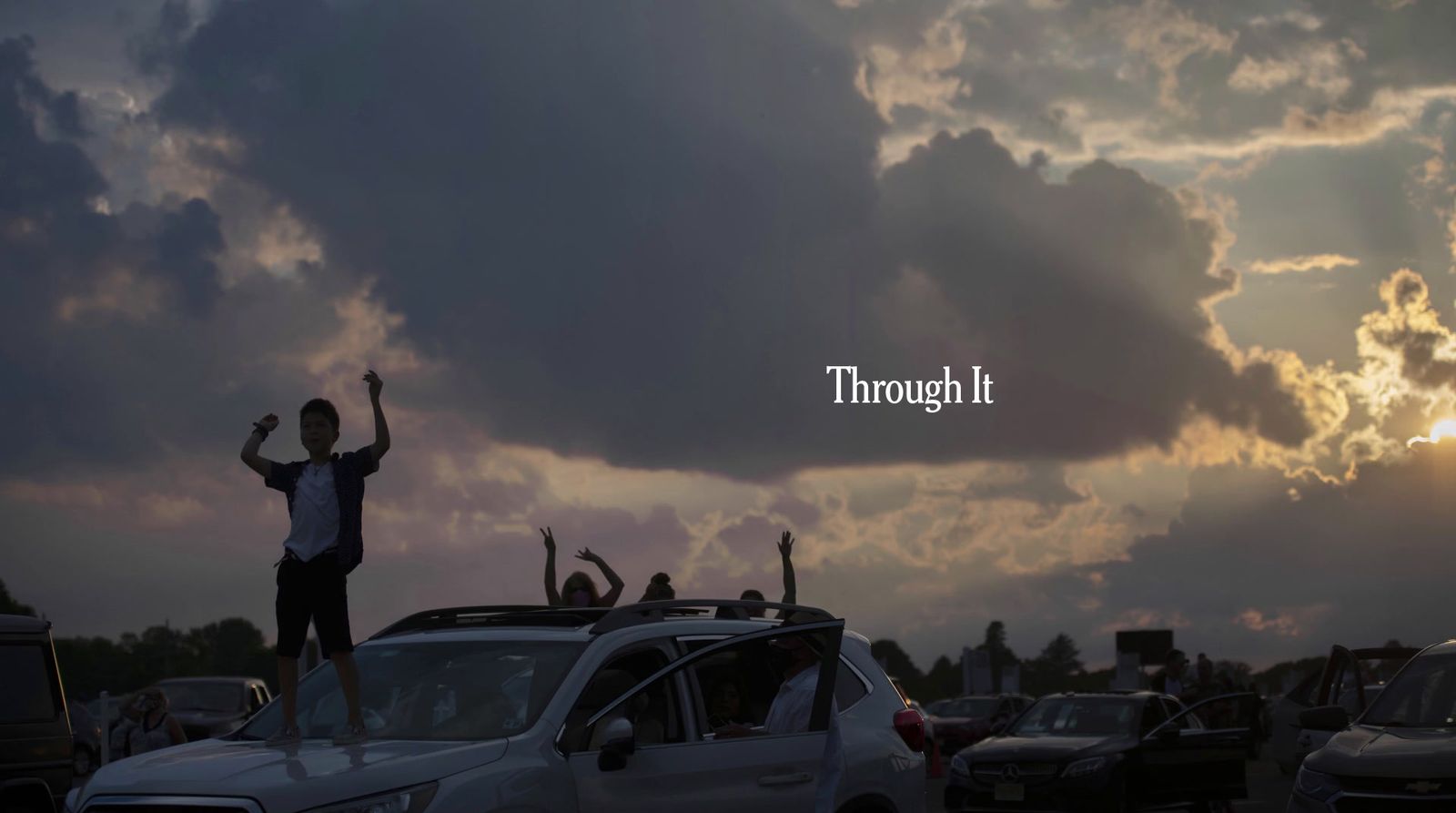 a man standing on top of a car in a parking lot