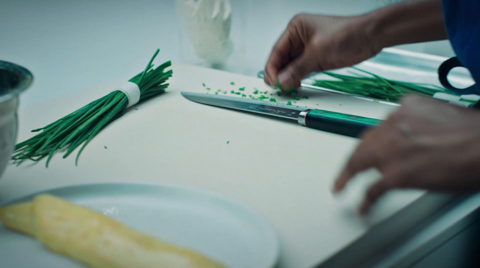 a person cutting up green onions on a cutting board