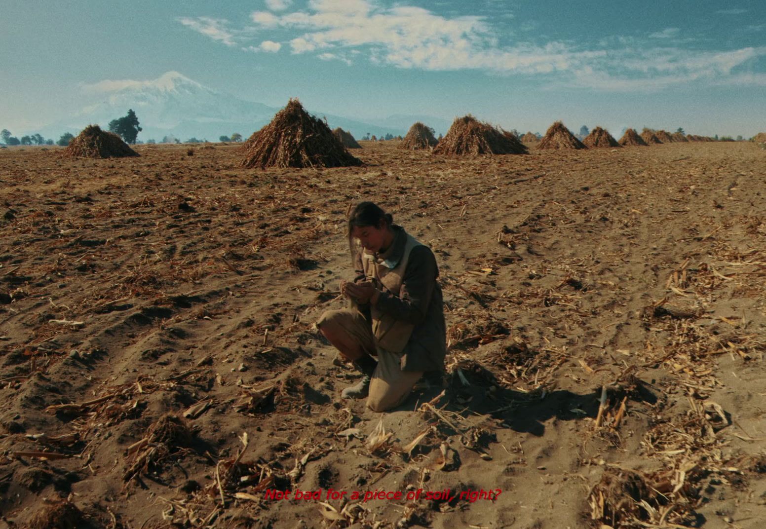 a man kneeling down in the middle of a field