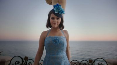 a woman in a blue dress standing next to the ocean