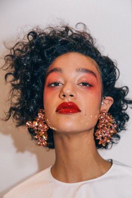 a woman with red lipstick and large earrings