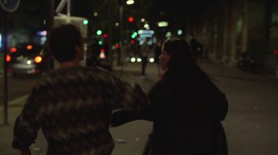 a man and a woman walking down a street at night