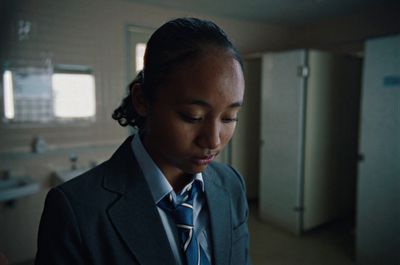 a woman wearing a suit and tie in a bathroom