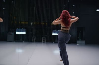 a woman with red hair standing in front of a mirror