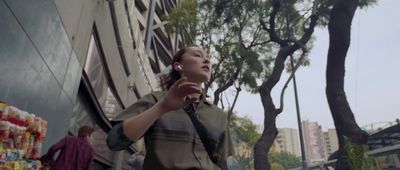 a woman walking down a street next to a tall building