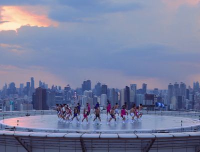 a group of dancers are dancing in front of a cityscape