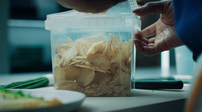 a plastic container filled with chips next to a plate of green beans