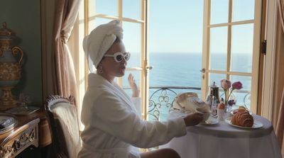 a woman in a bathrobe sitting at a table in front of a window