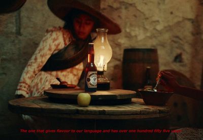 a woman sitting at a table with a bottle of beer