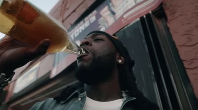 a man drinking a glass of beer in front of a building