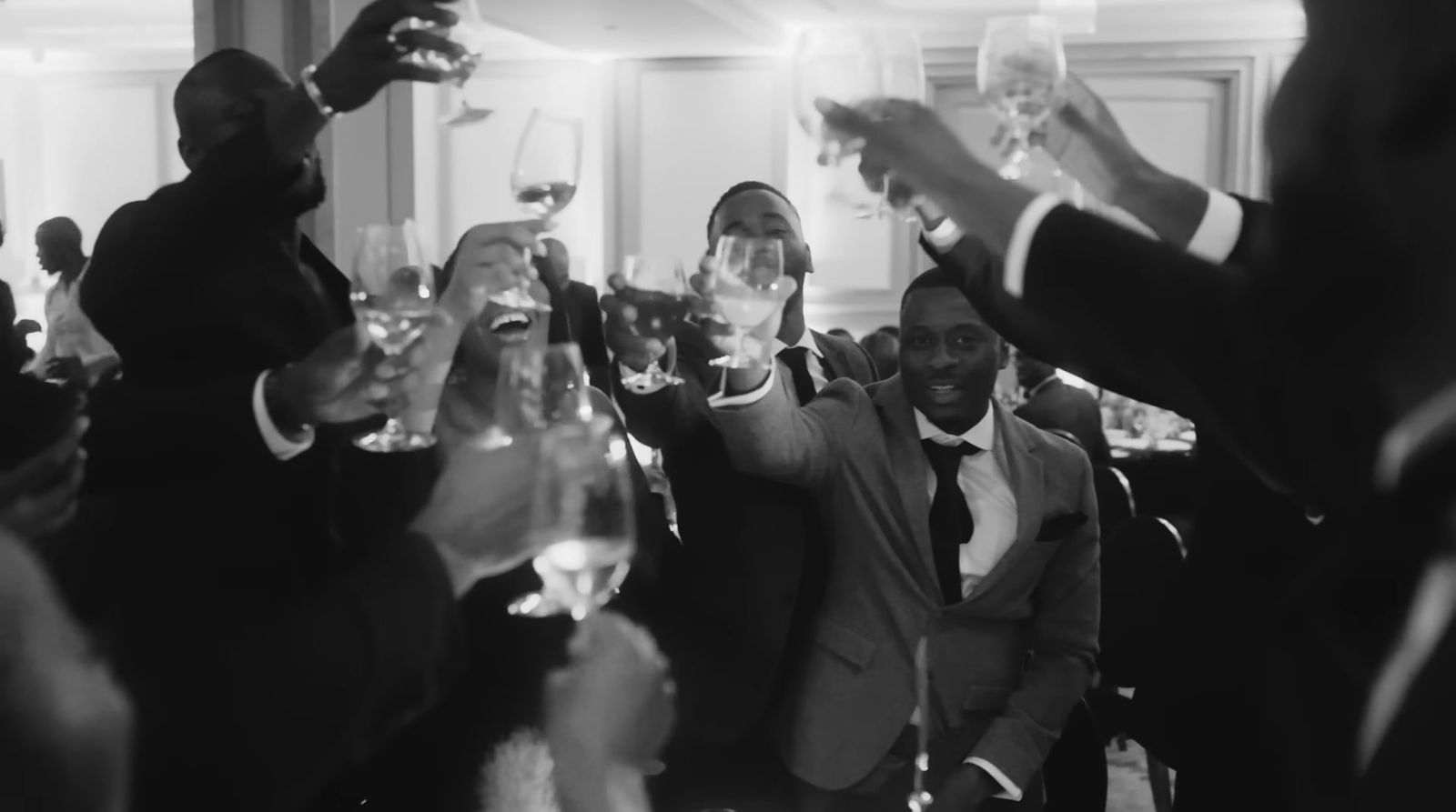 a black and white photo of a group of people toasting with wine glasses