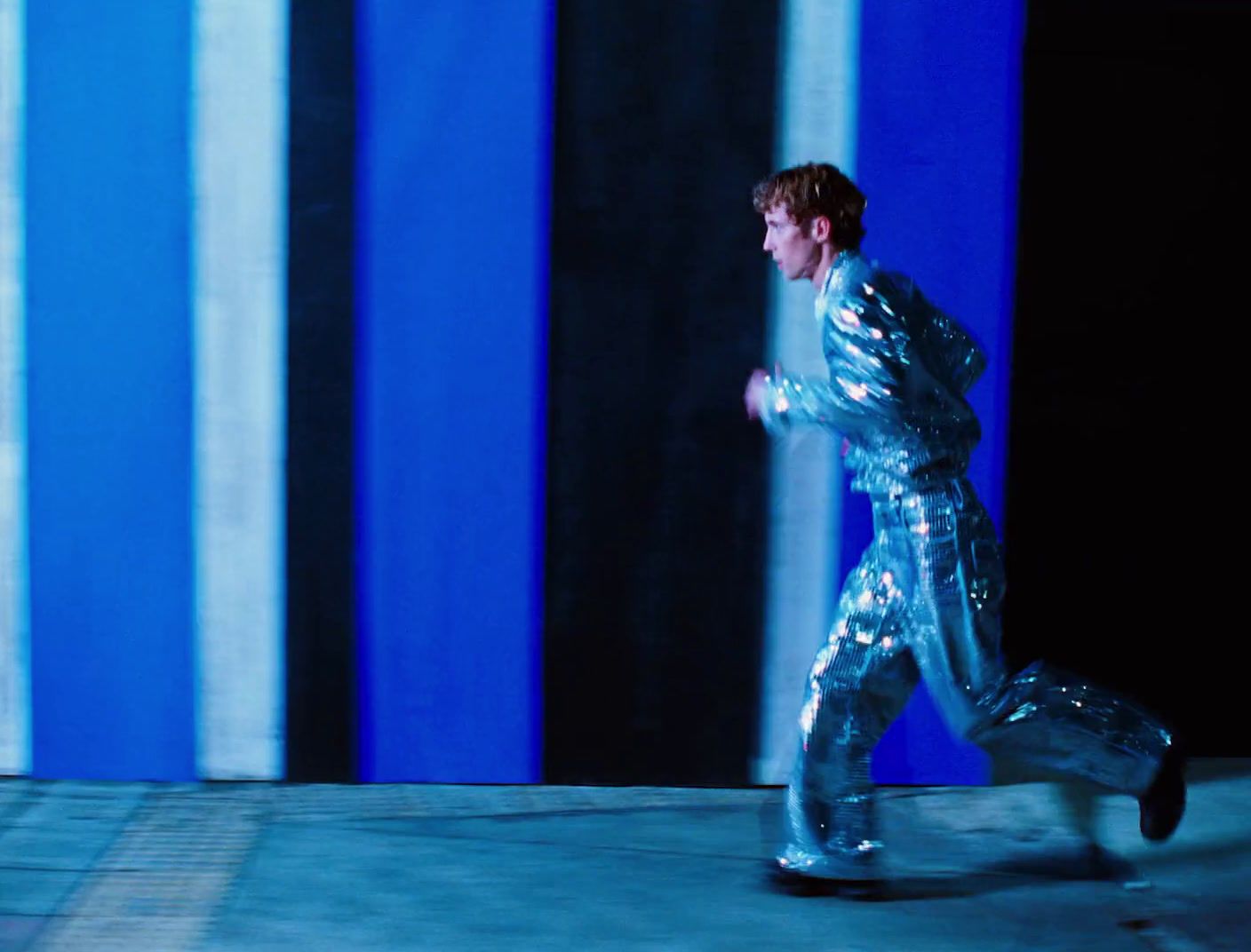 a man in a shiny silver suit running