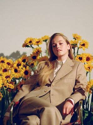 a woman sitting in a chair in front of a bunch of flowers