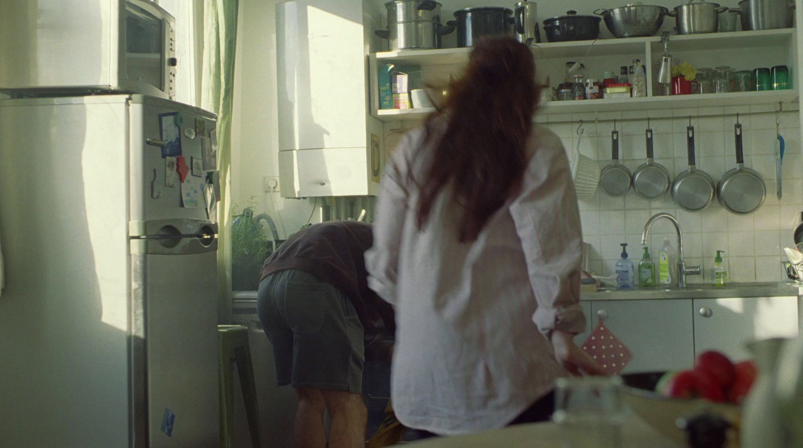 a woman standing in a kitchen next to a refrigerator