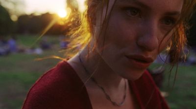 a woman in a red shirt standing in a field